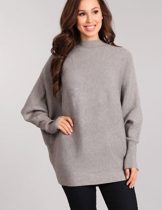 Woman wearing the Celeste Cozy Pullover in gray, featuring a mock neck and dolman sleeves for a relaxed fit.