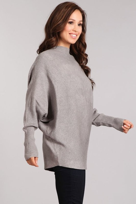 Woman in a cozy gray rib-knit pullover with dolman sleeves and a mock neck, showcasing relaxed style.