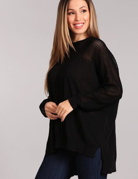 Black oversized crew neck sweater with hi-low hem and fishnet inset, styled with jeans.