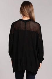 Back view of a black oversized sweater with a fishnet inset and hi-low hemline, showcasing its trendy design.