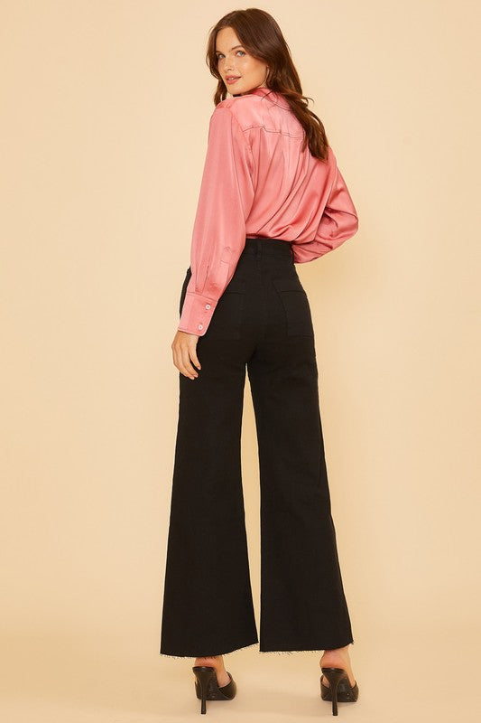 Woman wearing Renley Wide Leg Jean in black with a pink blouse, showcasing the high-rise and wide-leg design for a stylish look.