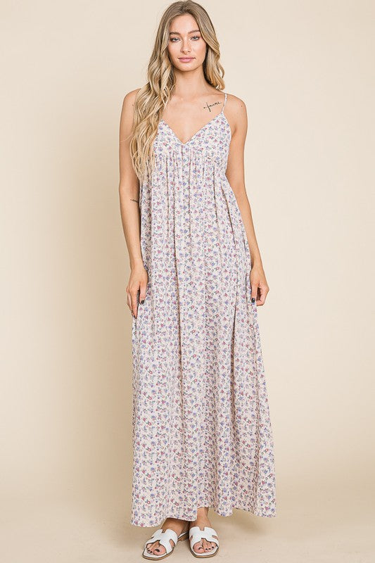 Woman wearing the Valencia Floral Dress, a sleeveless maxi dress with a floral print and back smocking detail.