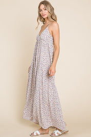 Model wearing the Valencia Floral Dress, a sleeveless maxi dress with a charming floral print and back smocking detail.