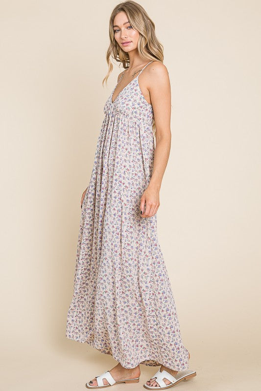 Model wearing the Valencia Floral Dress, a sleeveless maxi dress with a charming floral print and back smocking detail.