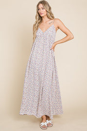 Model wearing the Valencia Floral Dress, a sleeveless maxi dress with a charming floral print and back smocking detail.