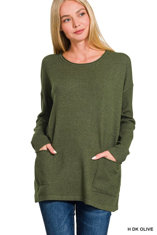 Woman wearing an olive Elara Two-Pocket Sweater with front pockets, paired with jeans for a casual-chic look.