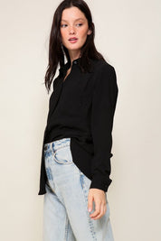 Woman wearing black Brooklyn Long Sleeve Blouse with light jeans, showcasing the blouse's elegant collared design and oversized fit.