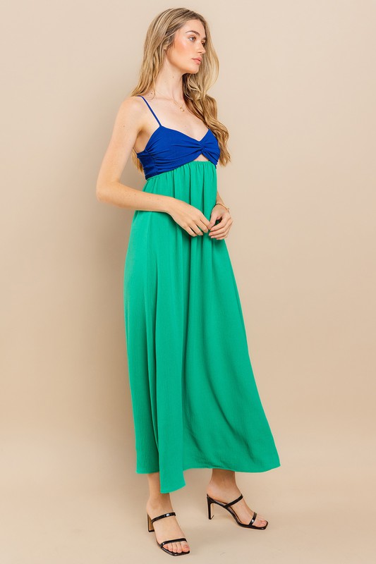 Model wearing the Clara Colourblock Dress, featuring a blue top and green skirt with a twist-front and adjustable straps.