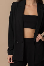 Woman wearing a black Piper Classic Blazer over a crop top, showcasing timeless sophistication and versatility.