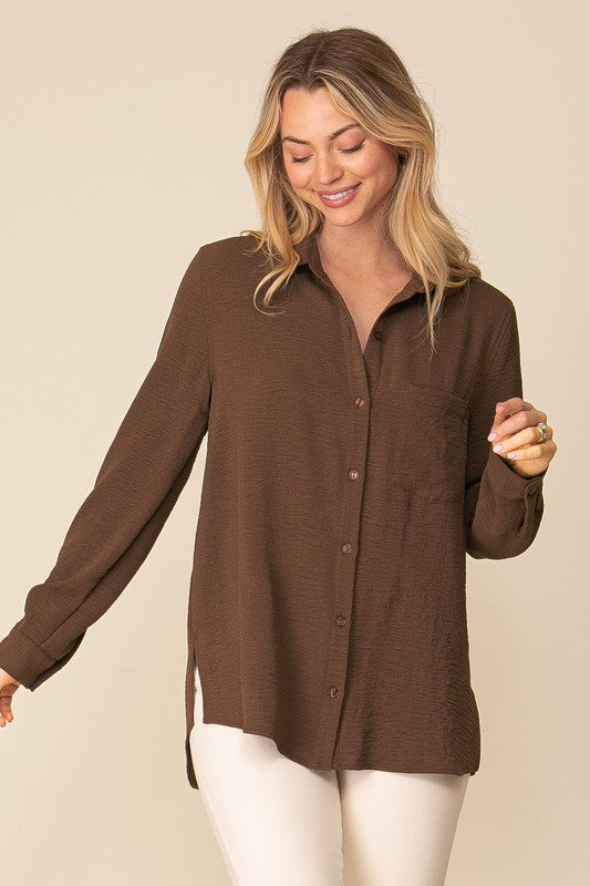 Woman wearing Brooklyn Long Sleeve Blouse in brown with collared neckline and button-down front for a stylish, comfortable look.