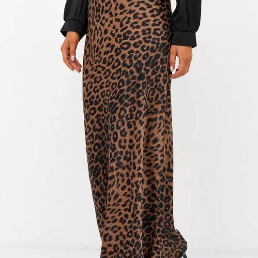 Woman wearing the Livia Leopard Satin Skirt, a long leopard-print skirt crafted from stretchy satin, paired with a black top and heels.