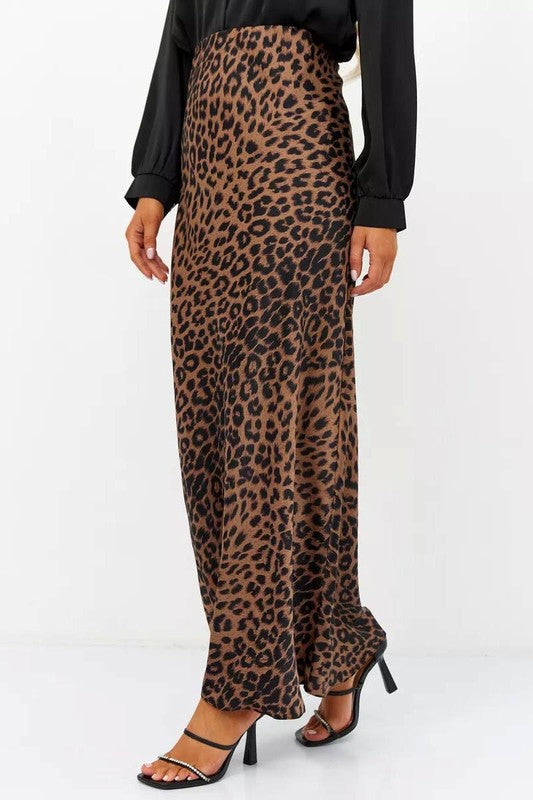 Woman wearing the Livia Leopard Satin Skirt, a long leopard-print skirt crafted from stretchy satin, paired with a black top and heels.