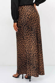 Woman wearing Livia Leopard Satin Skirt, showcasing its bold leopard-print design and flowing silhouette, paired with black top.