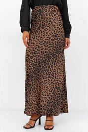 Woman wearing a Livia Leopard Satin Skirt, featuring a bold leopard print and long flowing silhouette, paired with a black top and heels.