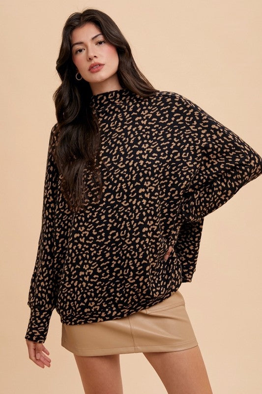 Woman wearing Kaida Leopard Sweater with animal jacquard knit and mock-neck, styled with a beige skirt against a neutral background.