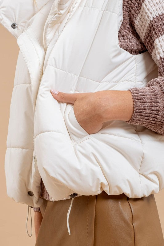 Woman wearing a quilted white puffer vest with functional pockets and a zip-up collar, layered over a sweater for a stylish look.