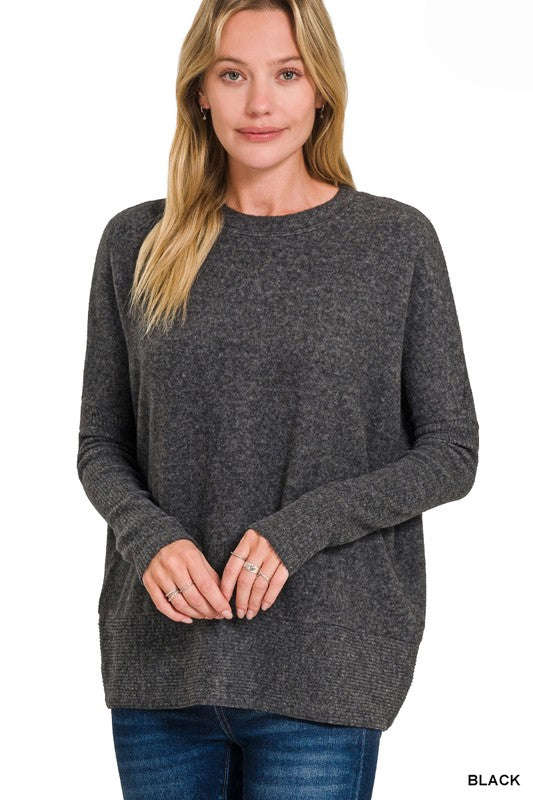 Woman wearing Camila Brushed Hacci Sweater in black with relaxed dolman sleeves and soft melange fabric, perfect for layering.