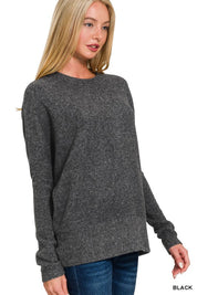 Woman wearing a Camila Brushed Hacci Sweater in black with dolman sleeves, showcasing cozy and stylish design.