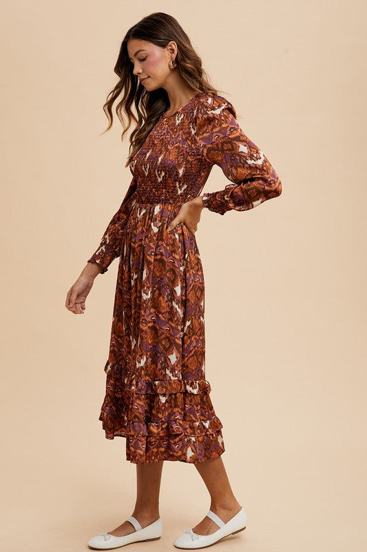 Woman wearing Sarai Dress with abstract print, smocked bodice, and long puff sleeves in side profile.