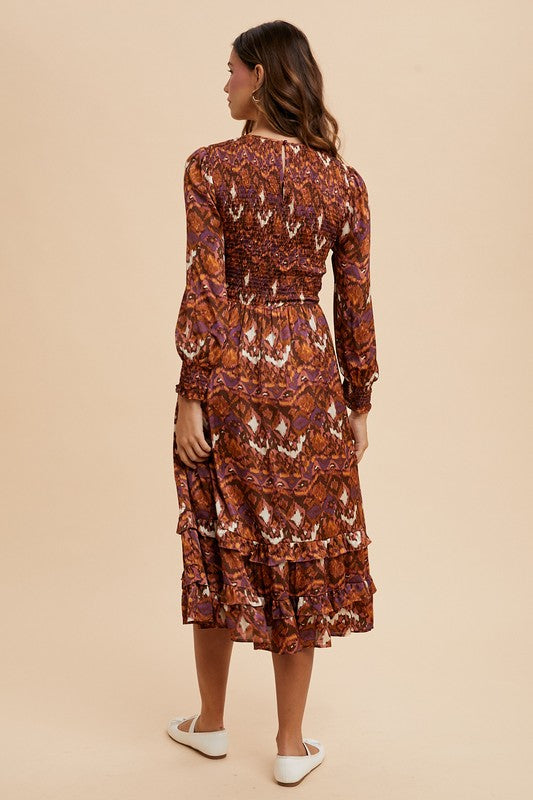 Woman wearing Sarai Dress with abstract print, long puff sleeves, and tiered skirt, showcasing back view for elegant style.