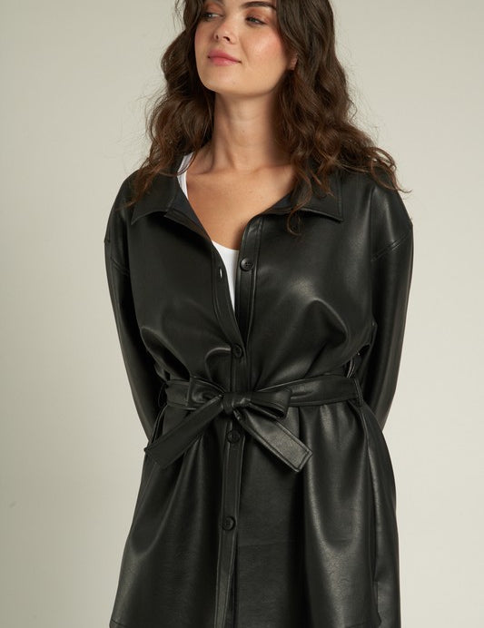 Woman modeling the Lyra Faux Leather Jacket, a trendy black shacket with a cinched waist and sleek finish.