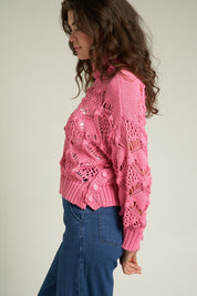 Model wearing the Scarlette Crochet Sweater in pink, showcasing its intricate crochet design and cropped style.