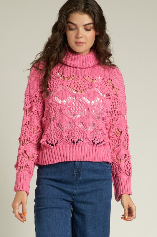 Cropped pink Scarlette Crochet Sweater with turtleneck, featuring intricate crochet design paired with high-waisted jeans.