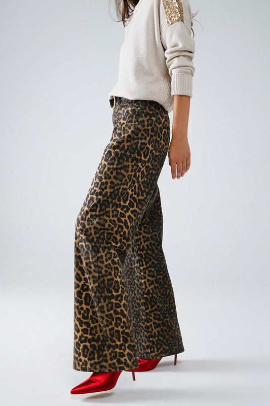 Model showcasing Lynx Denim Pants with bold leopard print, styled with a chic sweater and red heels.