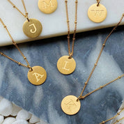 Singular Charm Initial NecklaceGold plated coin initial necklace. Absolutely adorable for engraved charm with dainty chain that has tiny balls in between. Has great quality and details. Stainless steel gold plated. Lead and Nickel Free 16 inch chain with