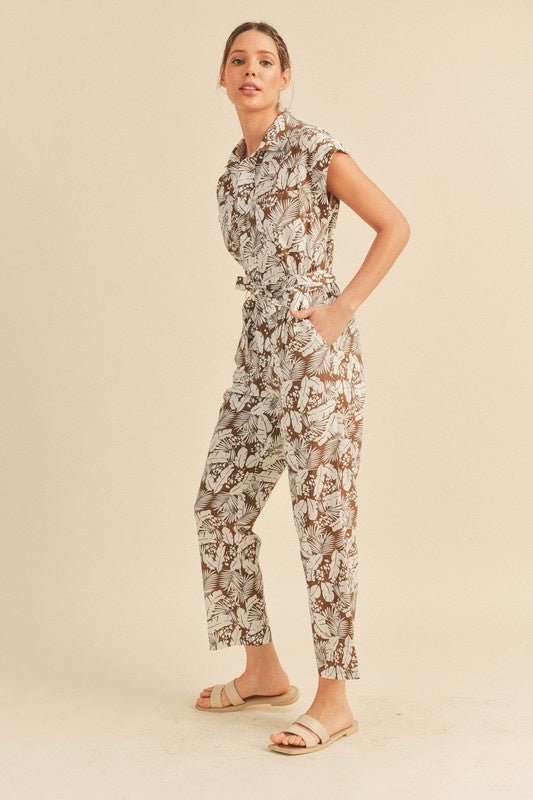 Viana Button Down Jumpsuit - FINAL SALEBe ready for adventure in the Viana Jumpsuit! This utility inspired jumpsuit features a summery botanical print with a button front top with chest pockets, a partially elasticated waist with a tie, and a straight leg