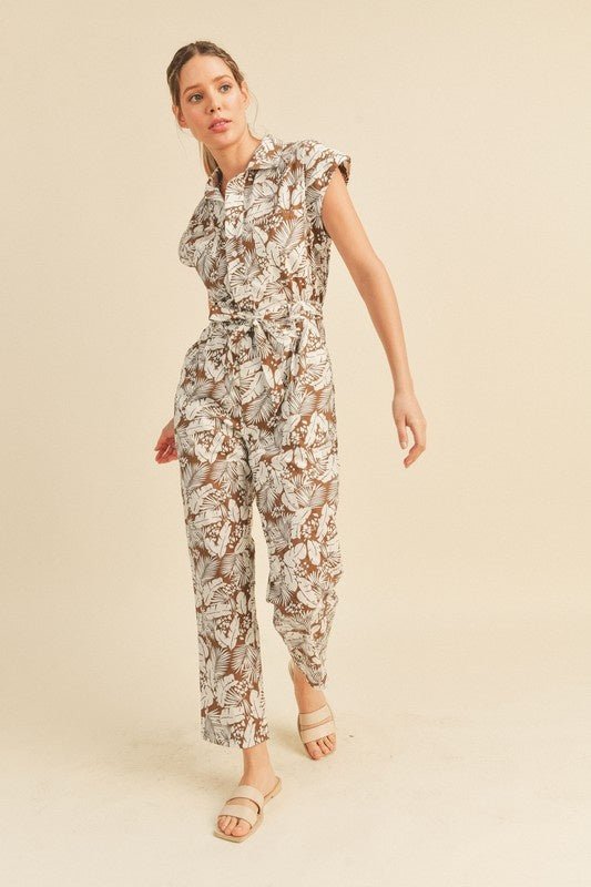 Viana Button Down Jumpsuit - FINAL SALEBe ready for adventure in the Viana Jumpsuit! This utility inspired jumpsuit features a summery botanical print with a button front top with chest pockets, a partially elasticated waist with a tie, and a straight leg