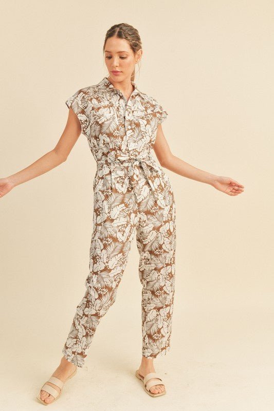 Viana Button Down Jumpsuit - FINAL SALEBe ready for adventure in the Viana Jumpsuit! This utility inspired jumpsuit features a summery botanical print with a button front top with chest pockets, a partially elasticated waist with a tie, and a straight leg