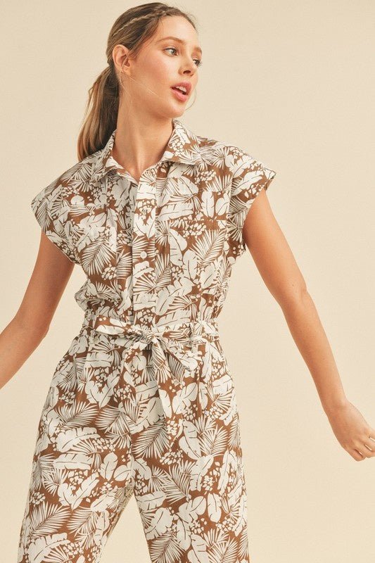 Viana Button Down Jumpsuit - FINAL SALEBe ready for adventure in the Viana Jumpsuit! This utility inspired jumpsuit features a summery botanical print with a button front top with chest pockets, a partially elasticated waist with a tie, and a straight leg